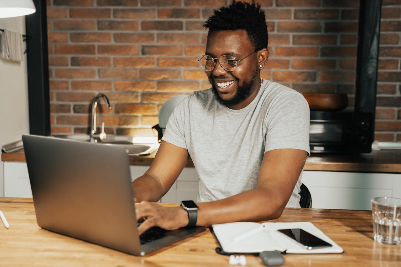 Home African American man smiling while working remotely on laptop from home office